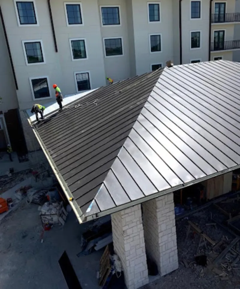 Crew installing standing seam metal roof panels on a commercial project in Plumsted